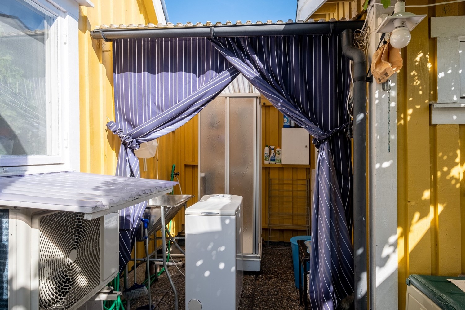 Duschkabin och tvättmaskin mellan stugan och friggeboden