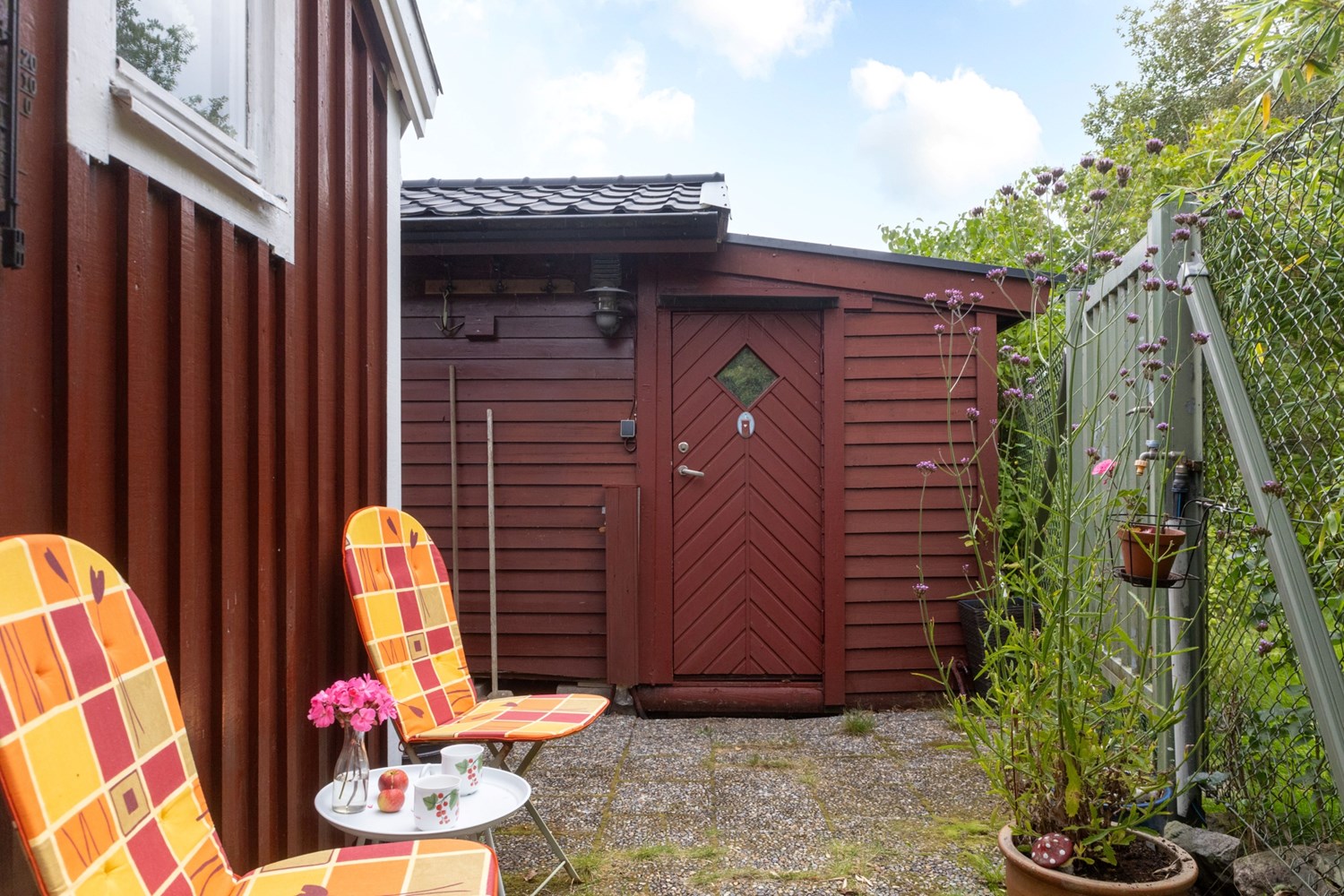 Baksidan har en dörr i stängsel, frigggeboden