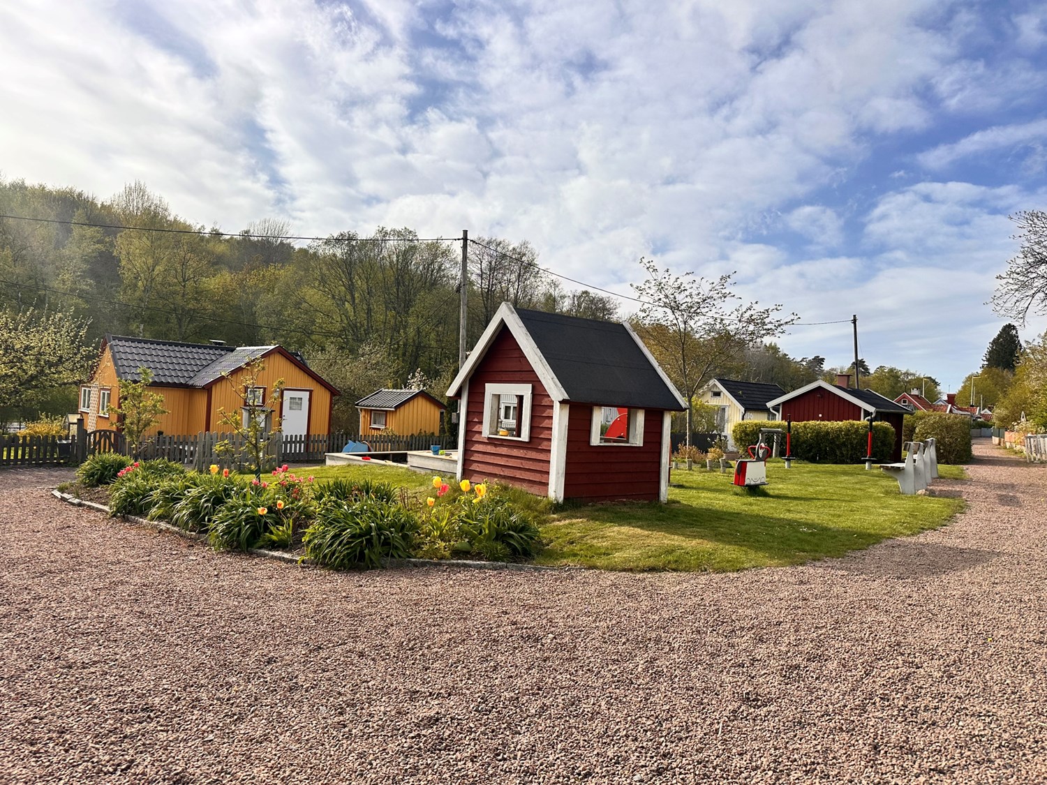 Vy över lekplatsen och stugan bakom