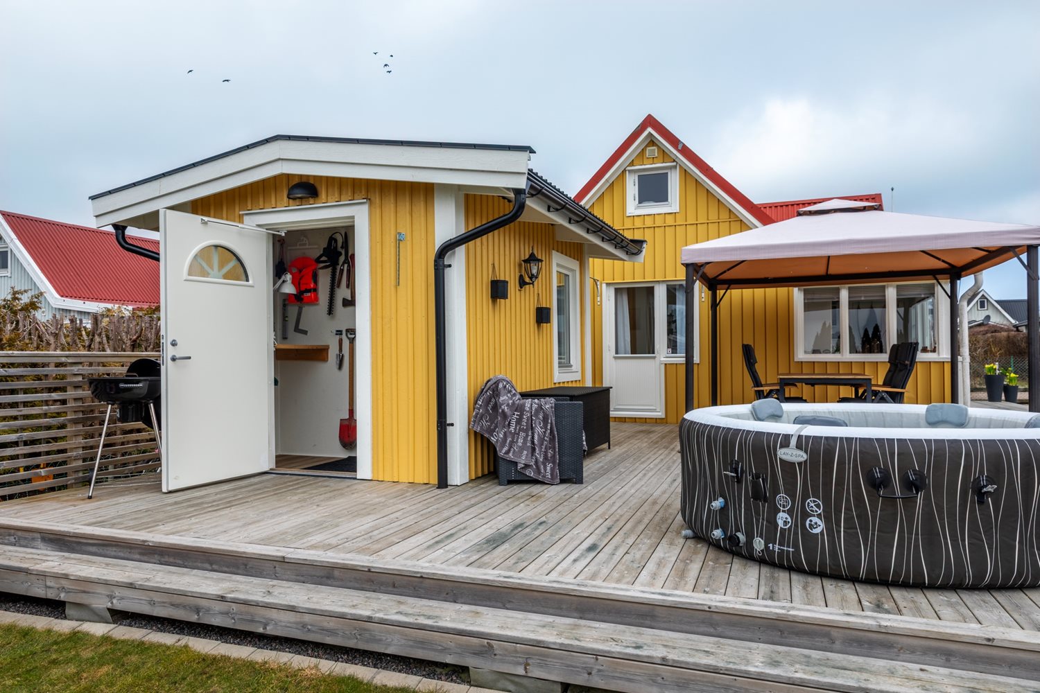 Vy från trädgården mot förrådet och stugan