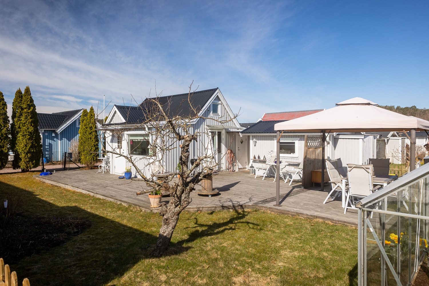 Vy inifrån trädgården mot stugan och uteplatsen