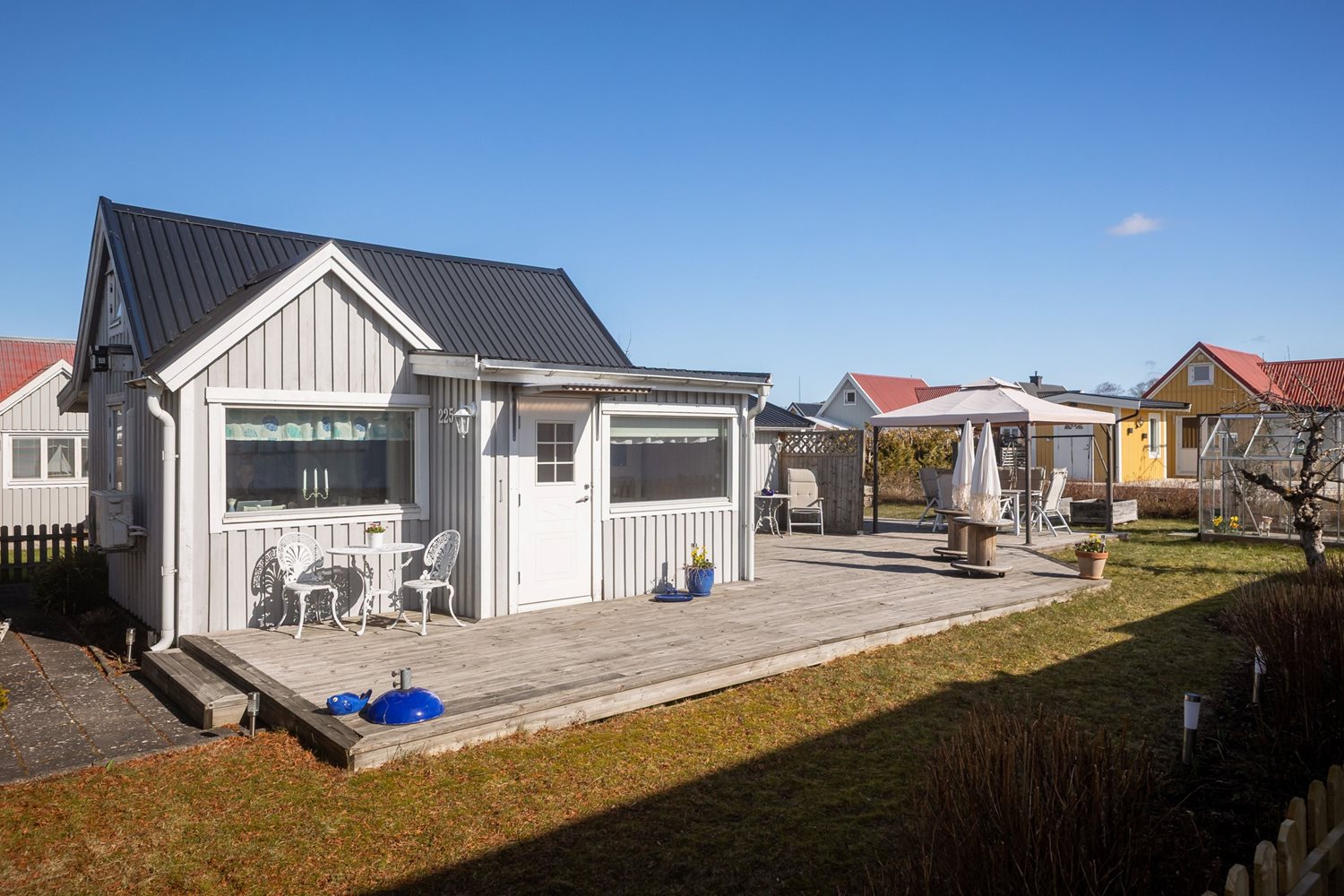 Vy från trädgård mot entren av stugan