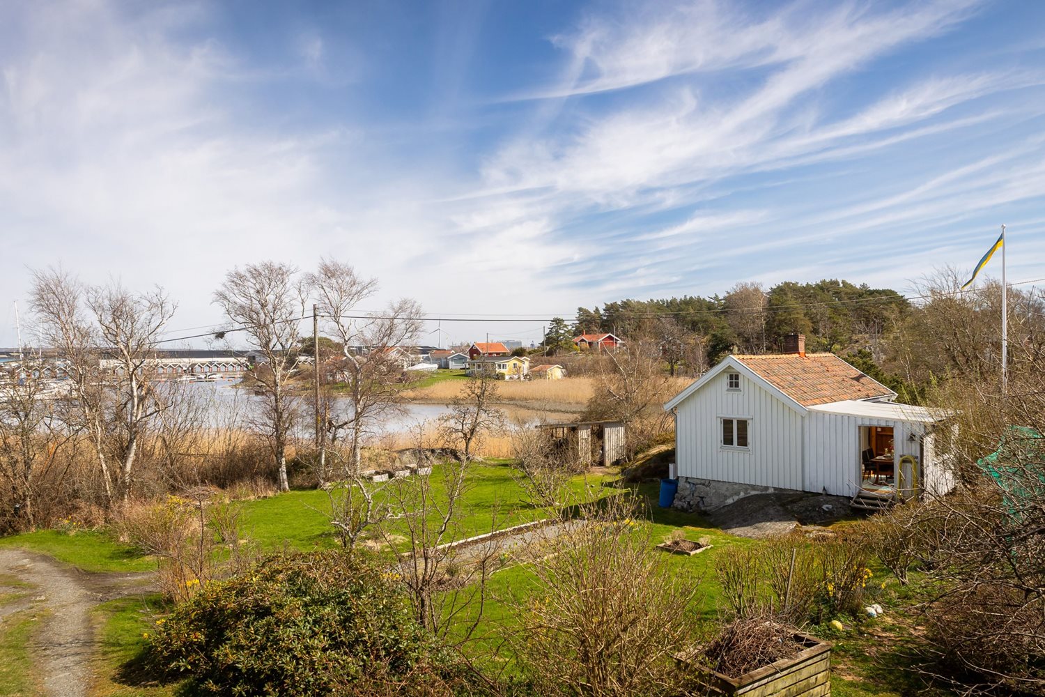 Tidig vårbild med vy från komplementsbyggnad mot stugan och utsikten