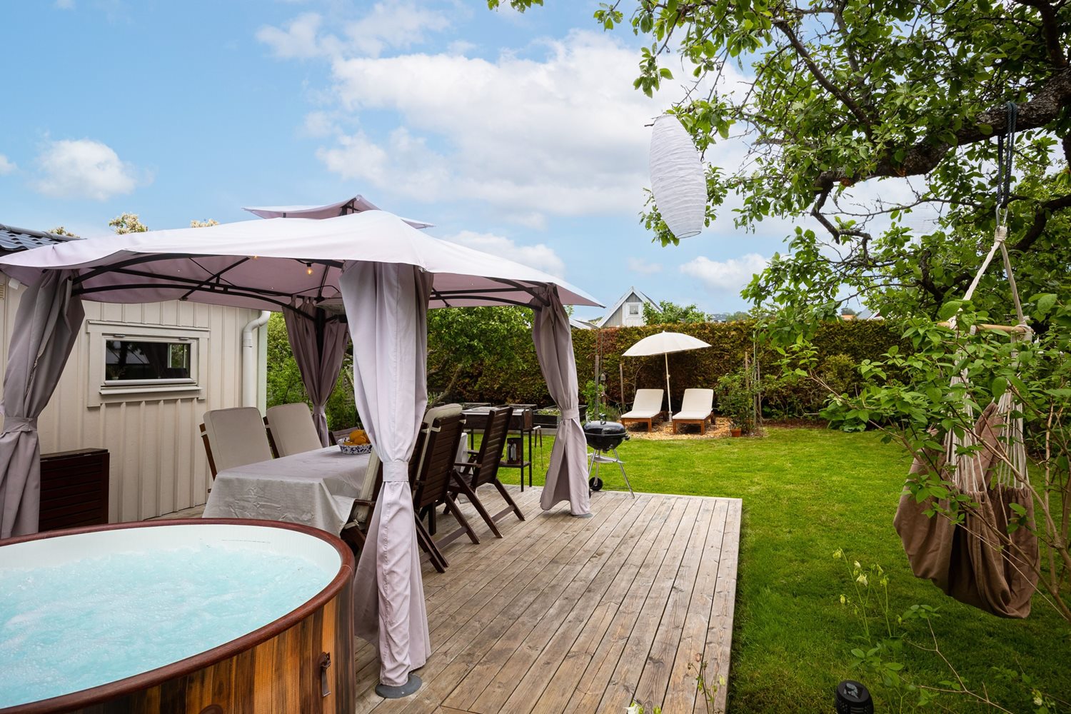 Vy mot trädgård och pergola och spabad