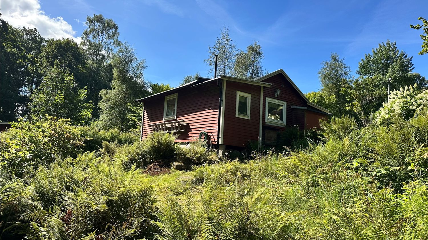 Baksidan av stugan där trädgården ligger i etage